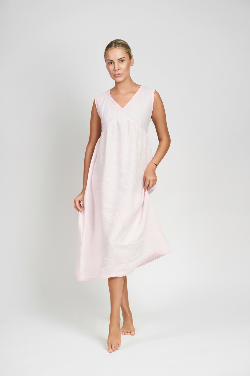 Kobieta w jasnoróżowej lnianej koszuli nocnej z dekoltem w kształcie litery V na jasnym tle
