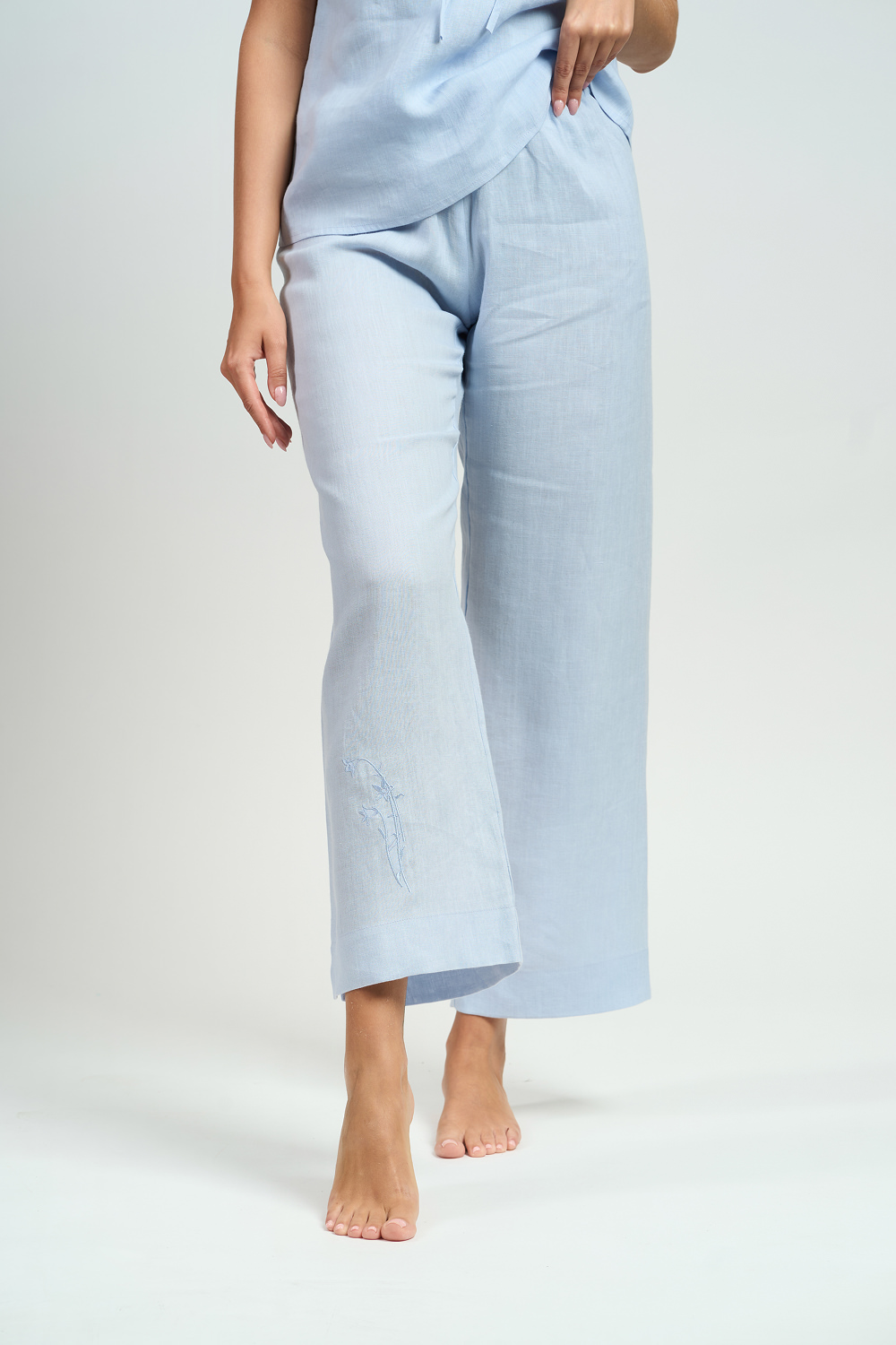 Zbliżenie na błękitne lniane spodnie piżamowe z delikatnym haftem na nogawce