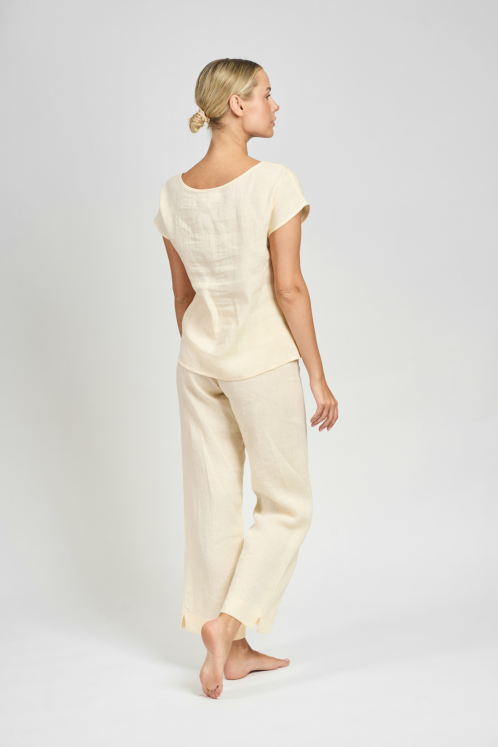 Kobieta w kremowym lnianym komplecie widziana od tyłu, z bluzką z krótkim rękawem